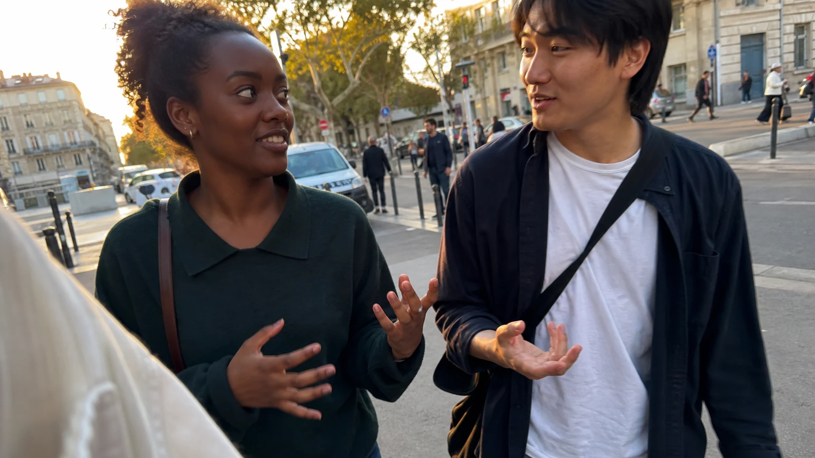 Un jeune couple échange en marchant dans une rue de Marseille au soleil couchant