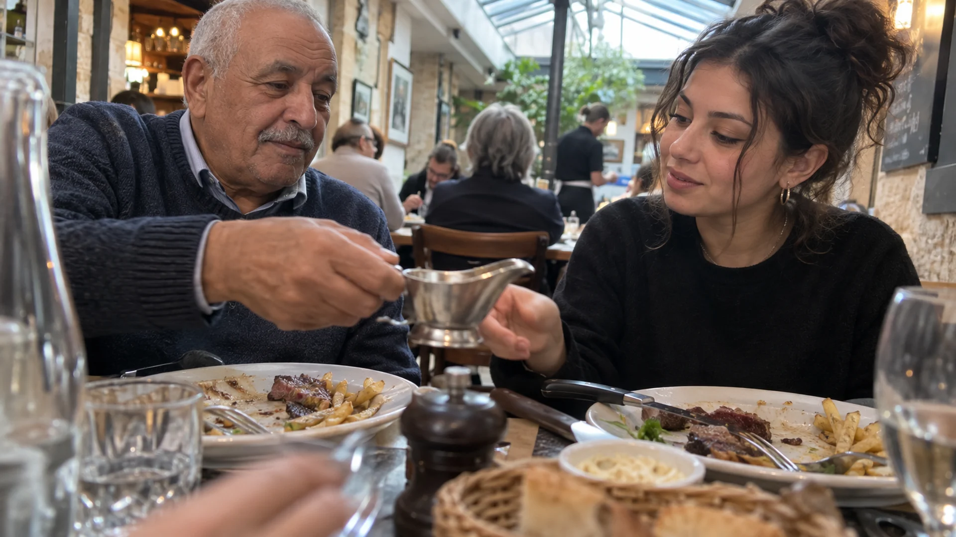 Une saucière passe entre deux personnes attablées dans une petite brasserie